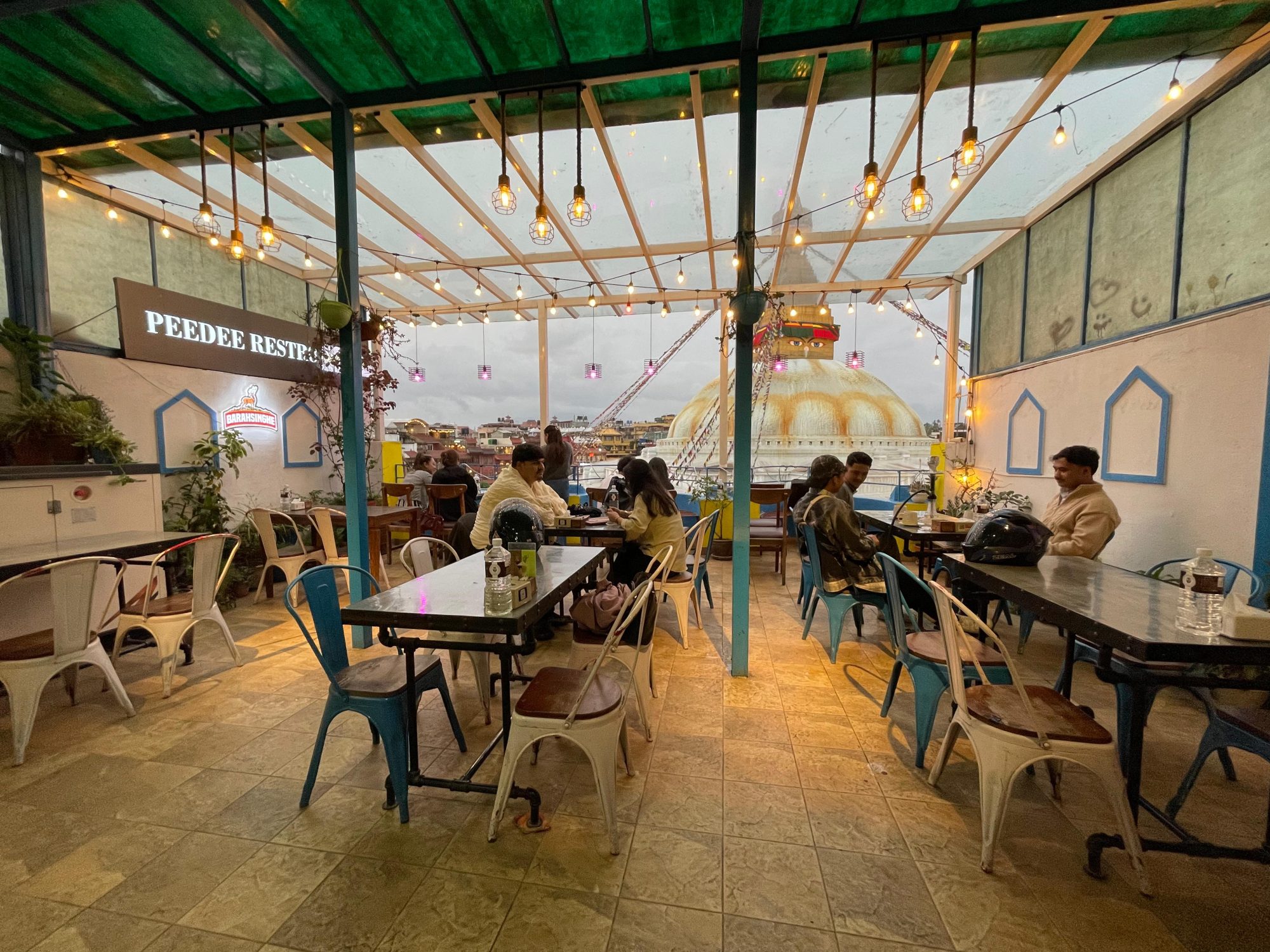 Open-air rooftop seating beneath warm string lights at golden hour