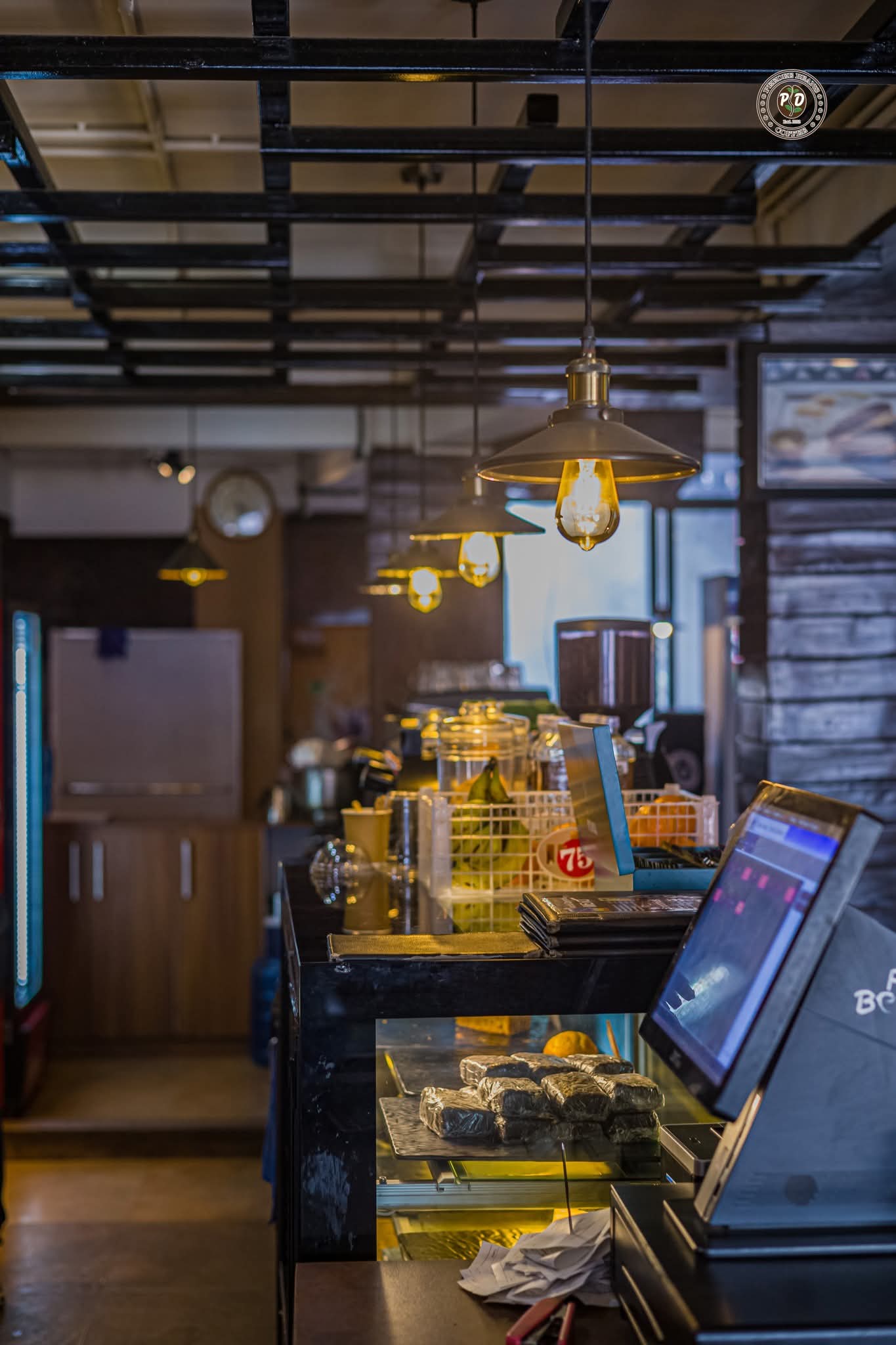 The PeeDee Beans counter — pendant lights and display jars, captured in soft amber